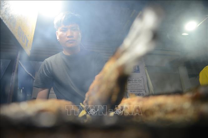Nhân viên tất bật nướng cá xuyên đêm xho Ngày vía Thần Tài, mùng 10 tháng Giêng. Ảnh: Mạnh Linh - TTXVN