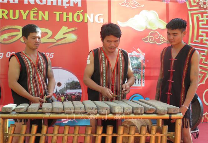 Nghệ nhân ưu tú A Thu hướng dẫn các thanh niên đánh đàn đá. Ảnh: Dư Toán – TTXVN 