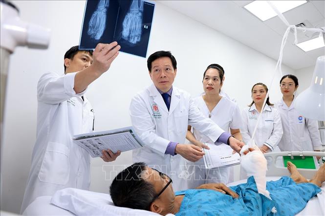 Bác sĩ Hoàng cùng ê kíp kiểm tra phim chụp X-quang một bệnh nhân sau ca phẫu thuật. Ảnh: Tuấn Anh - TTXVN 