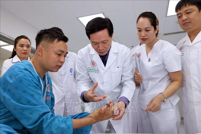 Bác sĩ Hoàng hướng dẫn bệnh nhân tập các động tác sau khi phẫu thuật. Ảnh: Tuấn Anh - TTXVN