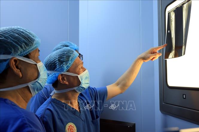 Bác sĩ Hoàng cùng kíp mổ xem phim X-quang trước khi tiến hành phẫu thuật. Ảnh: Tuấn Anh - TTXVN