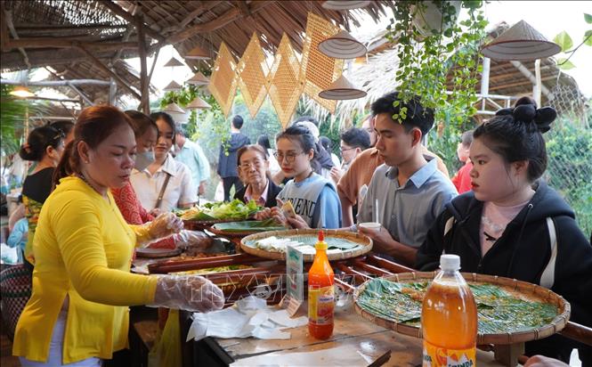 Người dân, du khách đến tham quan, thưởng thức nhiều món ăn ngon tại chợ quê Tân Thuận Đông. Ảnh: Nhựt An - TTXVN