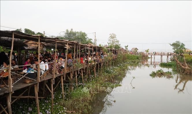 Người dân, du khách thưởng thức món ăn truyền thống tại chợ quê Tân Thuận Đông. Ảnh: Nhựt An - TTXVN