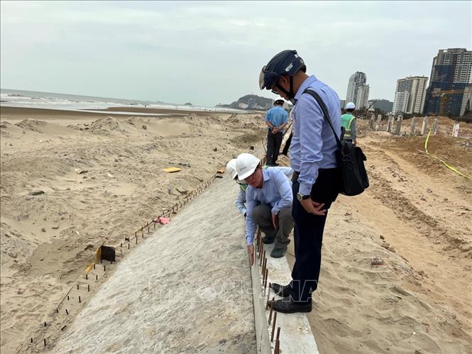 Phó Chủ tịch UBND thành phố Vũng Tàu Nguyễn Trọng Thụy kiểm tra, chỉ rõ lớp bê tông bảo vệ cốt thép kè biển không đủ độ dày. Ảnh: Đoàn Mạnh Dương-TTXVN