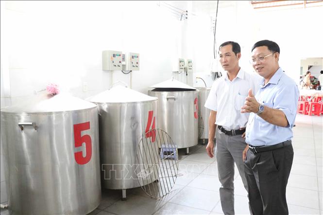 Ông Huỳnh Ngọc Xuân, Giám đốc Trung tâm Khuyến công và Xúc tiến thương mại Trà Vinh (phải) nghiệm thu các nồi nấu bánh tét bằng điện. Ảnh: Thanh Hòa- TTXVN