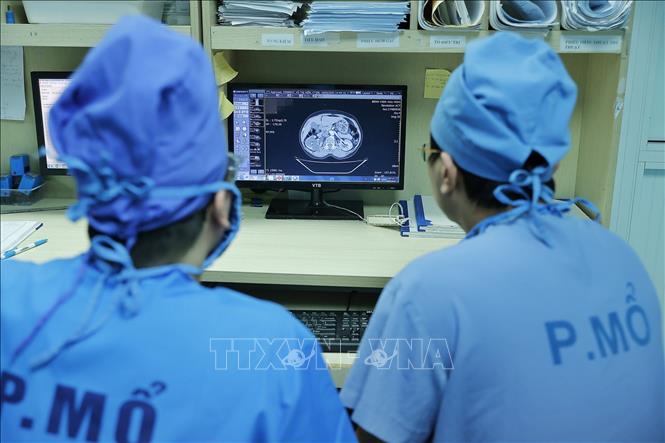 Bác sĩ Long cùng ê kíp xem hồ sơ bệnh án của bệnh nhân trước khi vào phẫu thuật. Ảnh: Minh Quyết – TTXVN