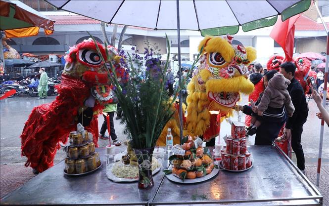 Đội lân sư rồng ghé qua mâm lễ của các gia đình chúc làm ăn đắc lộc. Ảnh: Anh Tuấn – TTXVN