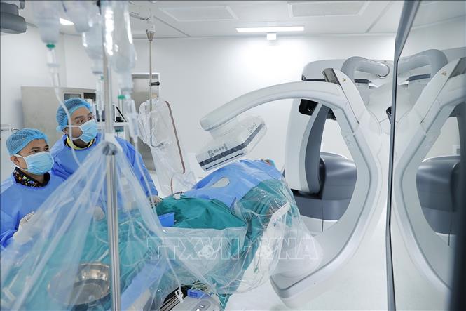 Ê kíp phẫu thuật đặt stent mạch vành cho bệnh nhân sử dụng cánh tay robot Artis Pheno. Ảnh: Minh Quyết - TTXVN