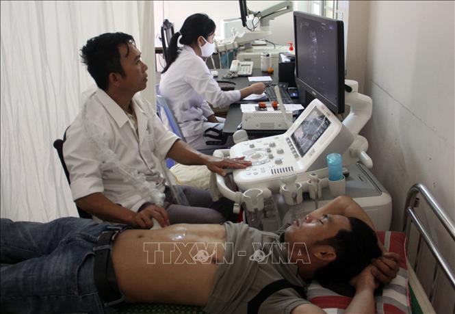 Y, bác sỹ Trung tâm y tế thành phố Tam Kỳ thăm khám cho bệnh nhân. Ảnh: Trịnh Bang Nhiệm - TTXVN 