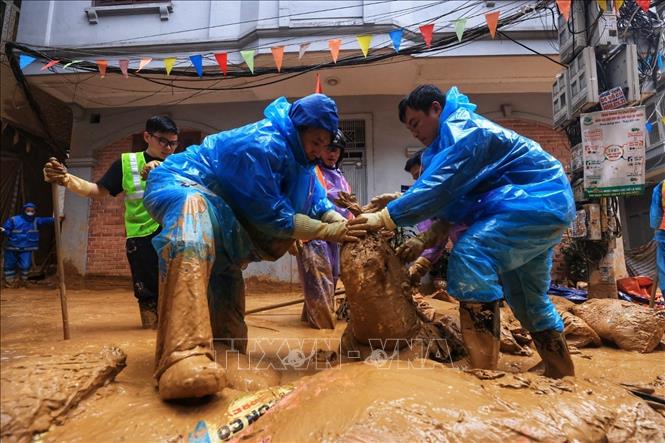 Công nhân đắp be bờ, quây bùn lại, dùng xe hút vệ sinh để hút sạch lượng bùn trào (ảnh chụp chiều 22/2). Ảnh: Tuấn Anh - TTXVN 