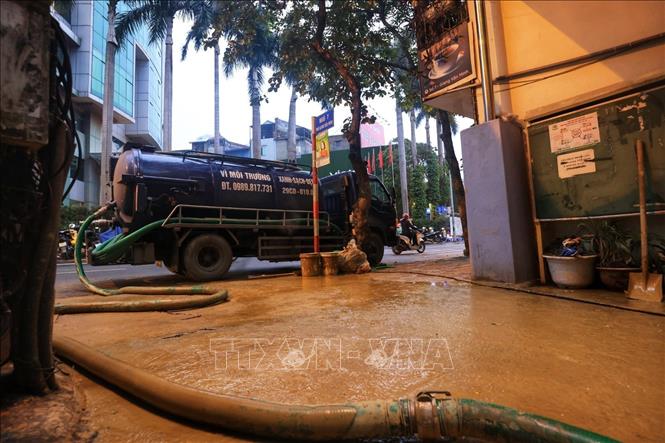 Xe hút vệ sinh đang hút lượng bùn trào ra tại ngõ 7 (ảnh chụp chiều 22/2). Ảnh: Tuấn Anh - TTXVN 