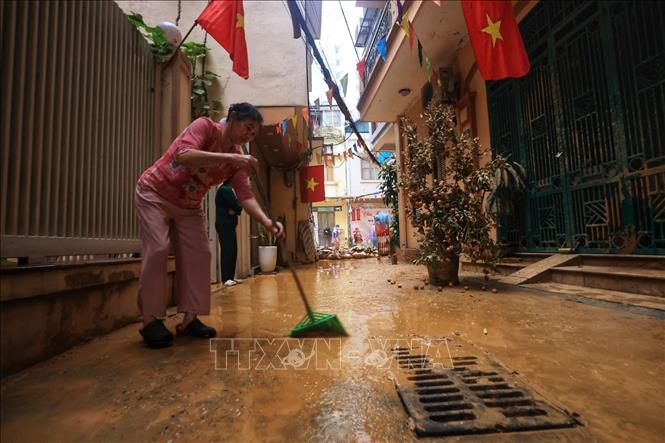 Người dân dọn dẹp vệ sinh sau khi lớp bùn nhão bị hút (ảnh chụp chiều 22/2). Ảnh: Tuấn Anh - TTXVN 