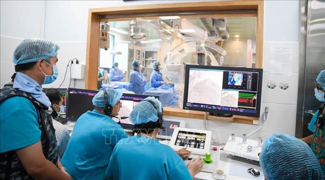 Các bác sĩ Bệnh viện Đột quỵ - Tim mạch thành phố Cần Thơ điều khiển robot từ bên ngoài để can thiệp mạch vành cho bệnh nhân bên trong phòng can thiệp. Sự kiện này đánh dấu cột mốc Việt Nam trở thành quốc gia đầu tiên ở Đông Nam Á sở hữu công nghệ,  thực hiện kỹ thuật cao này và đưa Việt Nam vào danh sách các quốc gia can thiệp mạch vành có sự hỗ trợ của robot. Ảnh: Ánh Tuyết - TTXVN