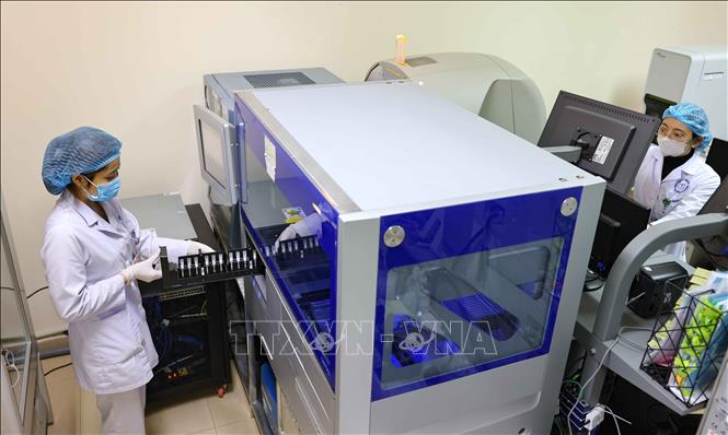 Nạp khay mẫu vào máy để thực hiện xác định nhóm máu trên máy tự động. Ảnh: Thanh Tùng - TTXVN