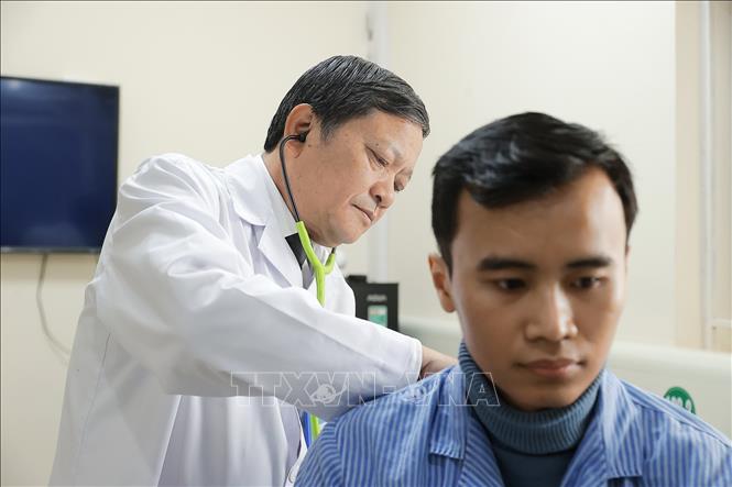 TTƯT.TS.BS. Đinh Văn Lượng thăm khám cho bệnh nhân Đặng Thái Mạnh (28 tuổi, ở Phú Thọ Hòa, Tân Phú, TPHCM), anh Mạnh đã được cùng gia đình đón cái Tết Ất Tỵ hồi sinh mà không phải thở oxy hàng ngày như 6 tháng trước. Ảnh: Minh Quyết – TTXVN