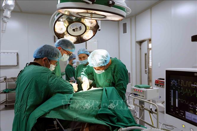 Tiến sĩ, bác sĩ Trần Hồng Vinh (bên phải) và đồng nghiệp tiến hành phẫu thuật cho bệnh nhân. Ảnh: Quang Quyết - TTXVN