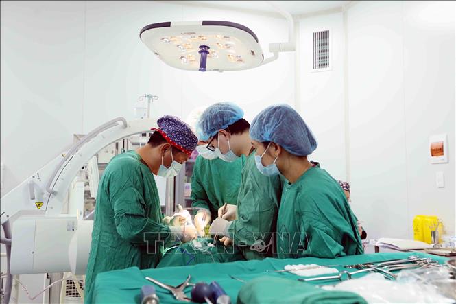 Tiến sĩ, bác sĩ Trần Hồng Vinh (bên trái) và đồng nghiệp tiến hành phẫu thuật cho bệnh nhân. Ảnh: Quang Quyết - TTXVN