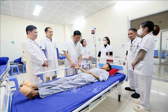 Tiến sĩ, bác sĩ Trần Hồng Vinh và đồng nghiệp thăm khám cho bệnh nhân. Ảnh: Quang Quyết - TTXVN