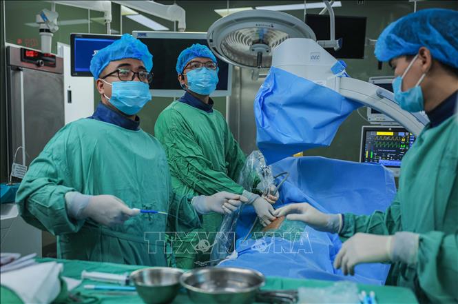 Ths.BS Vũ Khang Ninh - Phó trưởng Khoa Cấp cứu, Trưởng Bộ phận cấp cứu ngoại Bệnh viện Thanh Nhàn (giữa) cùng với các y, bác sĩ thực hiện ca mổ theo phương pháp mới. Ảnh: Hoàng Hiếu - TTXVN