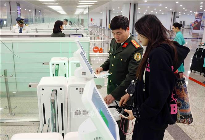 Cán bộ, chiến sĩ Cục quản lý xuất nhập cảnh hướng dẫn và hỗ trợ công dân sử dụng hệ thống Cổng xuất nhập cảnh tự động (Autogate) tại Sân bay quốc tế Nội Bài, Hà Nội. Ảnh: Phạm Kiên - TTXVN . Ảnh: Phạm Kiên - TTXVN