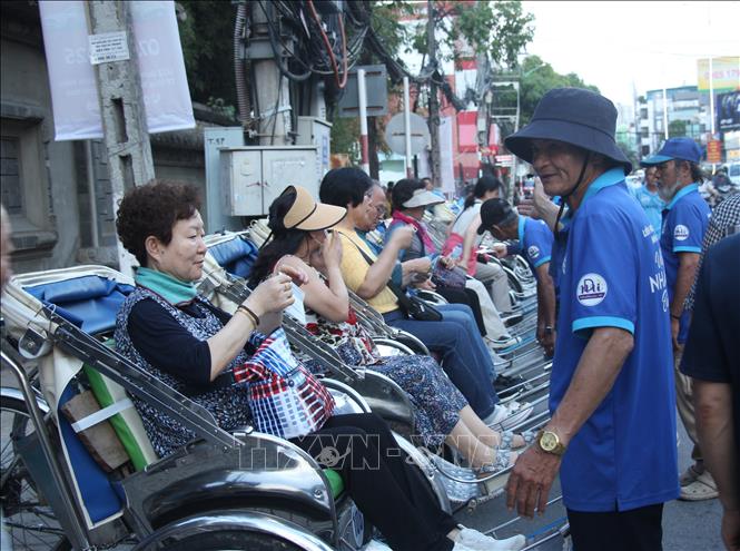 Người lao động hành nghề xích lô đón tiếp khách nước ngoài khi lên xe. Ảnh: Phan Sáu - TTXVN