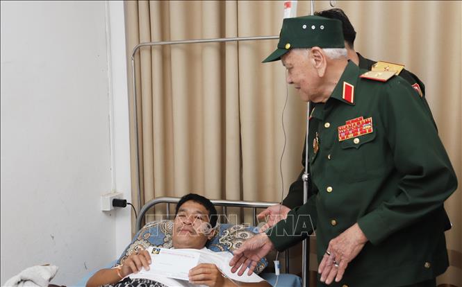 Thiếu tướng Võ Văn Chót, Trưởng ban danh dự Ban Liên lạc quân tình nguyện và chuyên gia quân sự Việt Nam giúp cách mạng Lào tỉnh Nghệ An, trao quà cho thương binh nặng đang điều trị tại Bệnh viện Trung ương Quân đội 103 Lào. Ảnh: Xuân Tú - PV TTXVN tại Lào