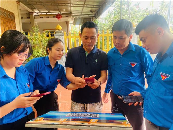 Đoàn viên thanh niên Hà Tĩnh đến tận nhà hướng dẫn người dân sử dụng thanh toán không dùng tiền mặt. Ảnh: TTXVN phát
