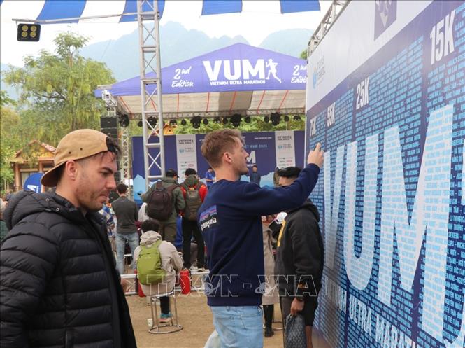 Các vận động viên trong và ngoài nước xem số báo danh trước ngày thi đấu. Ảnh: Thanh Hải - TTXVN