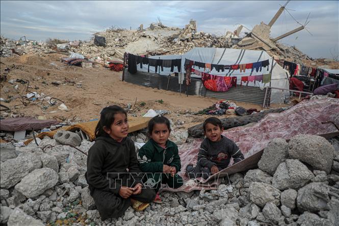 Các em nhỏ ngồi trên đống đổ nát của ngôi nhà bị phá hủy do xung đột tại Beit Lahia, Dải Gaza. Ảnh: THX/TTXVN