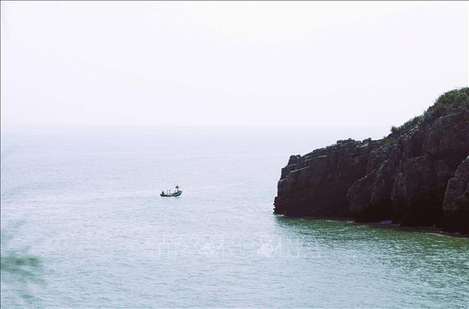 Thuyền đánh cá của ngư dân đi qua hang Mắt Rồng trên đường về lạch Quèn. Ảnh: Xuân Tiến - TTXVN 