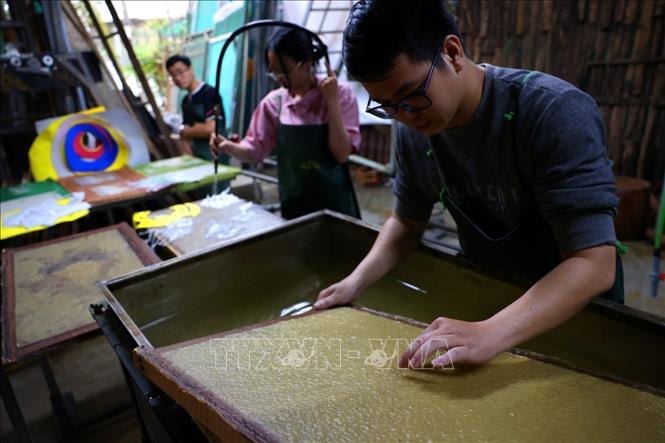 Công đoạn xeo giấy và chế tác với hoa văn được tạo khuôn sẵn. Ảnh: Phạm Hậu - TTXVN