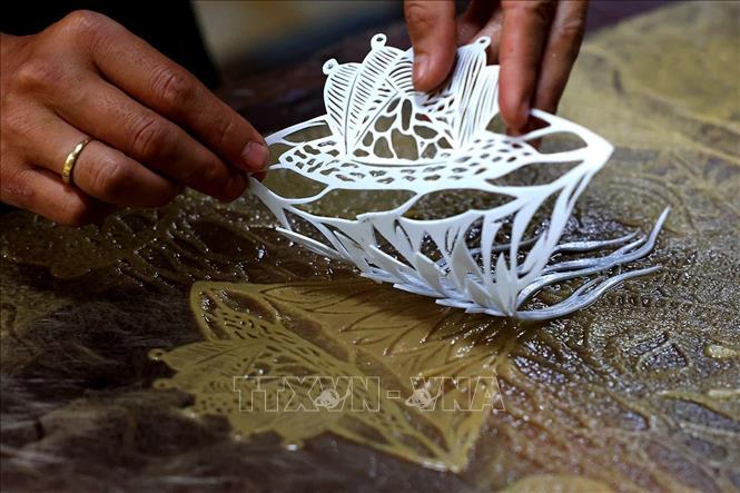 Tạo tác hình ảnh và các hoa văn theo ý tưởng của tác phẩm trên tấm giấy ướt. Ảnh: Phạm Hậu - TTXVN