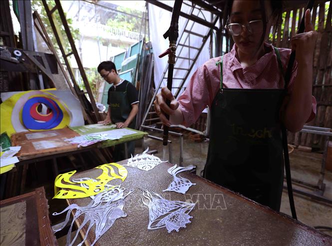 Người họa sĩ sử dụng phương pháp Trúc Chỉ graphy (vẽ bằng bút nước) để tạo độ dày mỏng cho giấy, cũng như độ chìm nổi của hoa văn dựa trên ý tưởng của mình. Ảnh: Vũ Sinh - TTXVN