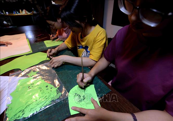 Họa sĩ trổ họa tiết theo ý tưởng để tạo nên một tác phẩm tranh Trúc Chỉ. Ảnh: Vũ Sinh - TTXVN