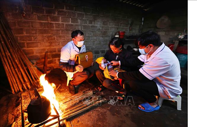 Bác sĩ Nguyễn Văn Hiệp ( bên phải) hướng dẫn cách chăm sóc trẻ sơ sinh tại nhà cho bà con dân tộc. Ảnh: Minh Đức – TTXVN
