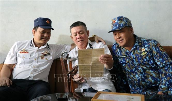 Những đồng đội trong Ban liên lạc Bộ đội Trường Sa Phú Yên xem lại giấy xuất ngũ của thương binh Trần Văn Hùng (thành phố Tuy Hòa), cựu chiến binh trong trận Gạc Ma. Ảnh: Xuân Triệu - TTXVN