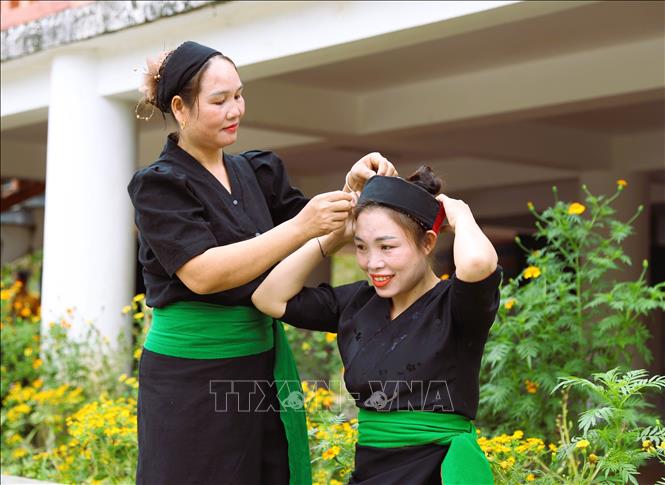 Phụ nữ dân tộc Ơ Đu ở bản Văng Môn giúp nhau sửa sang trang phục truyền thống để tham gia lễ hội tiếng sấm đầu năm. Ảnh: Xuân Tiến - TTXVN 
