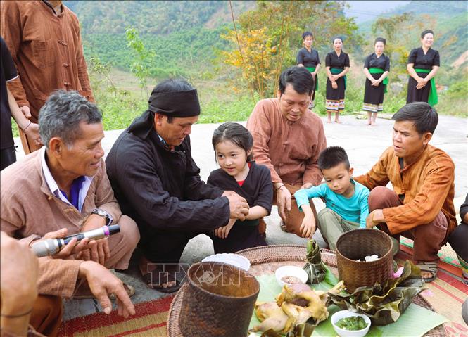 Ngoài việc cột chỉ cổ tay thì lễ đặt tên cho những cháu nhỏ trong bản cũng được thực hiện ngay sau khi kết thúc nghi thức cúng ở mâm làm vía cho dân bản. Ảnh: Xuân Tiến - TTXVN 
