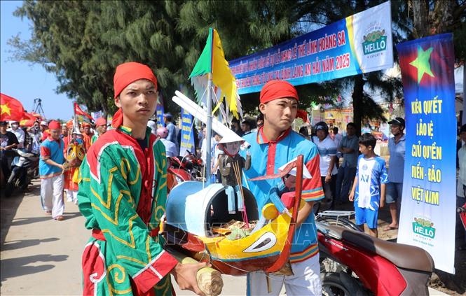 Các thanh niên ưu tú trong làng An Hải thực hiện nghi thức rước thuyền câu ra biển. Ảnh: Quốc Khánh - TTXVN