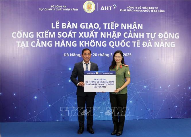 Ông Đỗ Trọng Hậu, Phó Tổng Giám đốc Công ty cổ phần Đầu tư và Khai thác Nhà ga quốc tế Đà Nẵng trao bảng tượng trưng bàn giao hệ thống Cổng kiểm soát xuất nhập cảnh tự động cho đại diện Cục quản lý xuất nhập cảnh. Ảnh: Trần Lê Lâm – TTXVN 