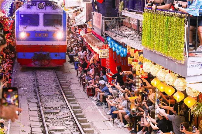 Du khách chen chúc tại các quán cà phê hai bên đường ray, háo hức chụp ảnh và tận hưởng cảm giác hồi hộp khi tàu đến. Ảnh: Ngọc Anh/TTXVN phát