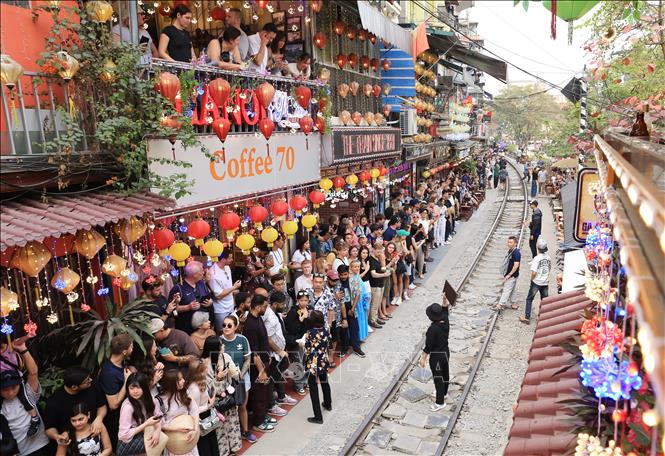Trước thời điểm tàu chạy qua, chủ các quán cà phê yêu cầu du khách ngồi sát vào bên trong tránh va chạm. Ảnh: Thành Phương - TTXVN
