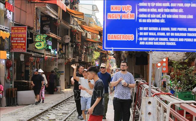 Du khách phớt lờ biển cảnh báo nguy hiểm khi đi lại trên tuyến đường sắt. Ảnh: Thành Phương - TTXVN