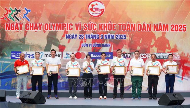Bà Trần Thị Diệu Thúy - Phó Chủ tịch UBND Thành phố Hồ Chí Minh trao bằng khen cho các tập thể, cá nhân có nhiều đóng góp trong việc tổ chức ngày chạy Olympic 2025. Ảnh: Trung Tuyến - TTXVN