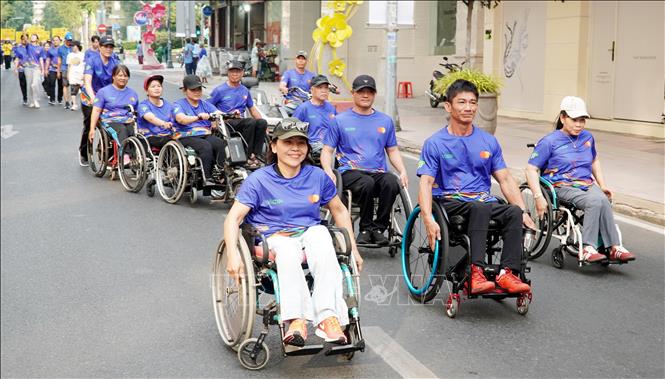 Hội viên Hội người khuyết tật tham gia di chuyển trên đường Đồng Khởi. Ảnh: Trung Tuyến - TTXVN