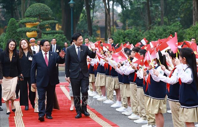 Prime Minister Pham Minh Chinh and his spouse host a ceremony to welcome Singaporean Prime Minister Lawrence Wong and his spouse in Hanoi on March 26. VNA Photo: Dương Giang