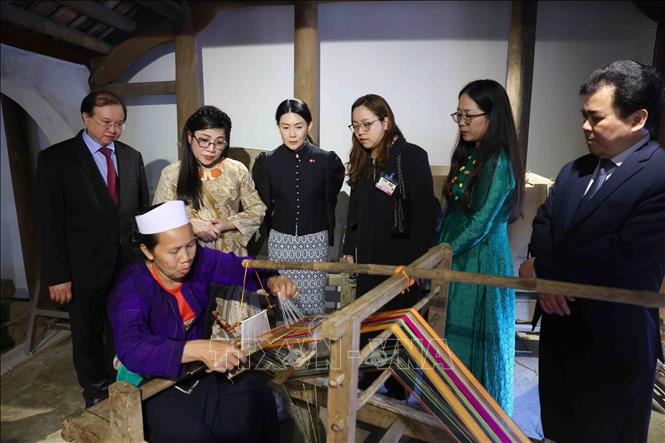 Bà Lê Thị Bích Trân, Phu nhân Thủ tướng Phạm Minh Chính và bà Loo Tze Lui, Phu nhân Thủ tướng Cộng hòa Singapore Lawrence Wong nghe Nghệ nhân giới thiệu về kỹ thuật dệt vải thổ cẩm. Ảnh: Phạm Kiên - TTXVN
