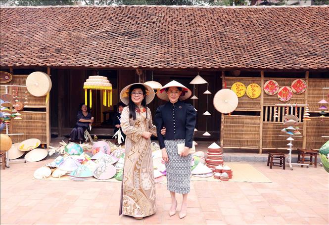 Bà Lê Thị Bích Trân, Phu nhân Thủ tướng Phạm Minh Chính cùng bà Loo Tze Lui, Phu nhân Thủ tướng Cộng hòa Singapore Lawrence Wong đội nón lá chụp ảnh lưu niệm tại Bảo tàng Dân tộc học Việt Nam. Ảnh: Phạm Kiên - TTXVN