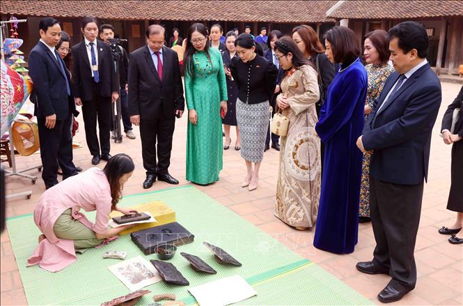 Bà Lê Thị Bích Trân, Phu nhân Thủ tướng Phạm Minh Chính và bà Loo Tze Lui, Phu nhân Thủ tướng Cộng hòa Singapore Lawrence Wong xem các nghệ nhân làm tranh Đông Hồ. Ảnh: Phạm Kiên - TTXVN