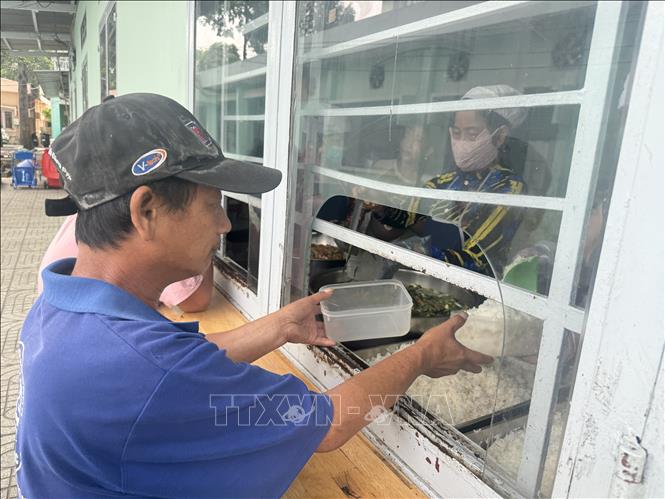 Người nhà bệnh nhân nhận bữa ăn miễn phí tại Bếp ăn tình thương trong khuôn viên Trung tâm y tế thành phố Thuận An (Bình Dương). Ảnh: Huyền Trang - TTXVN
